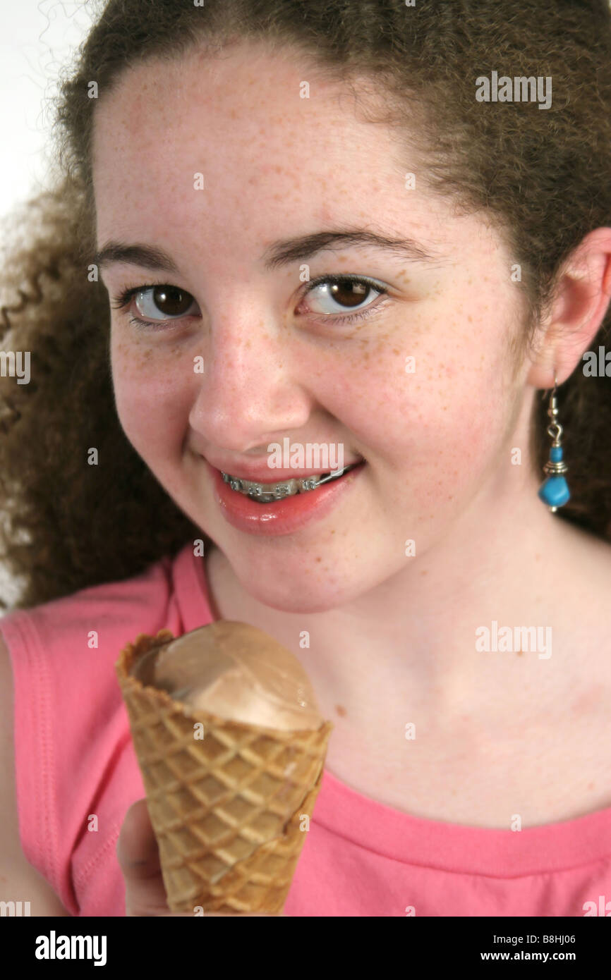 A cute teen girl with freckles and braces holding a chocolate ice Stock