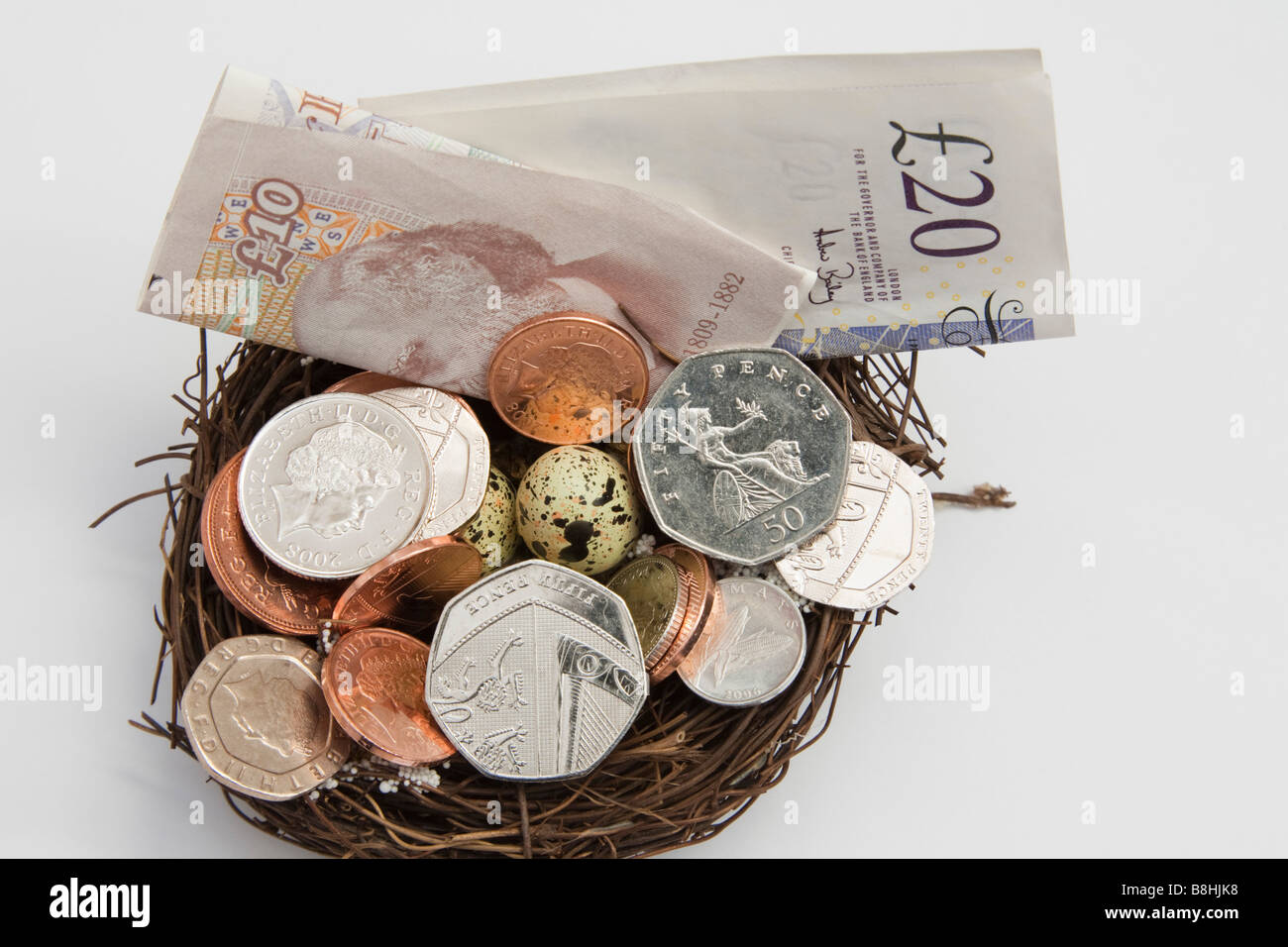 Pile of UK money in various denominations on an artificial nest with eggs from above. England Britain Stock Photo
