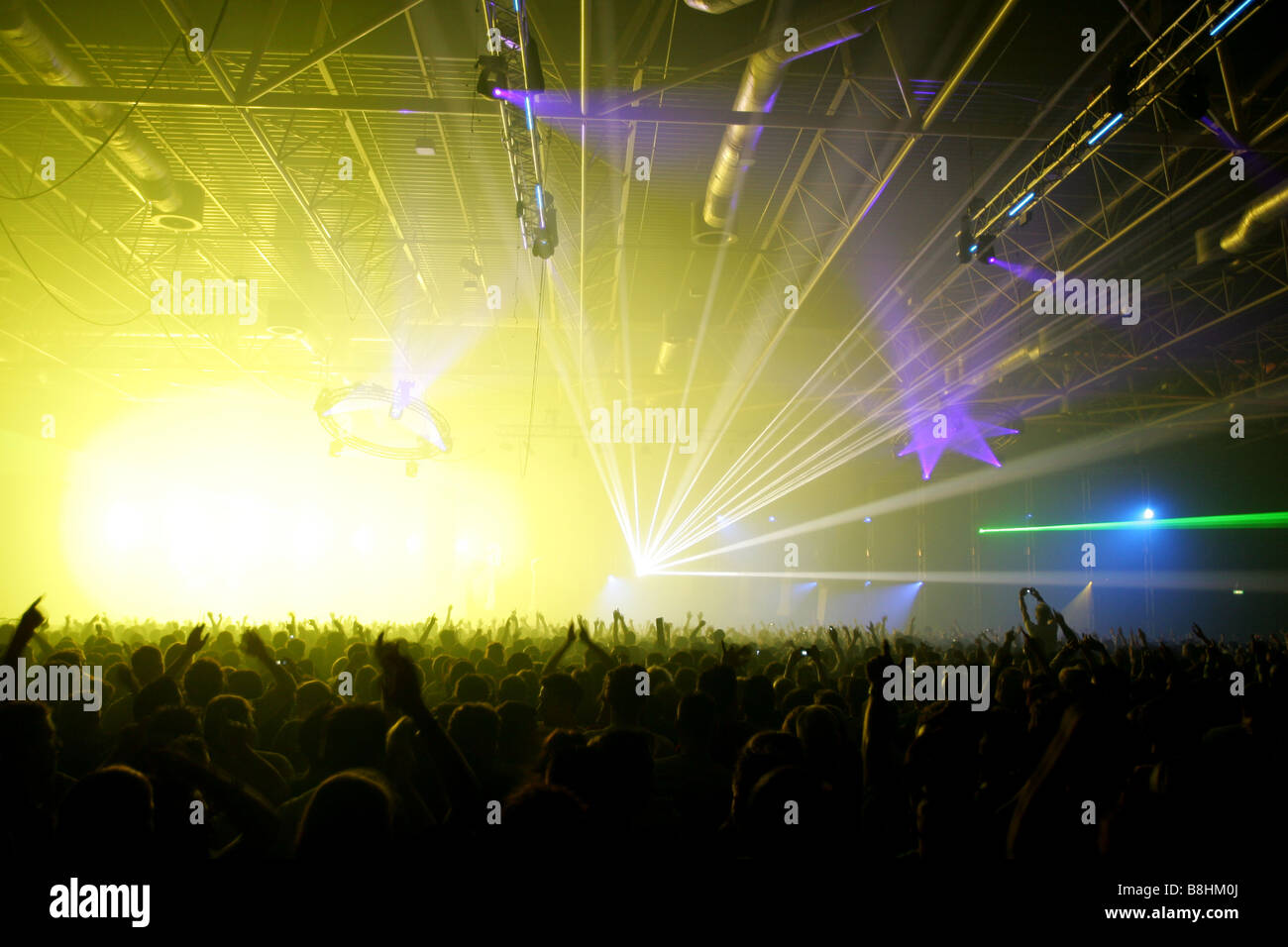 Large crowd and colorful lights and lasers at a houseparty in the