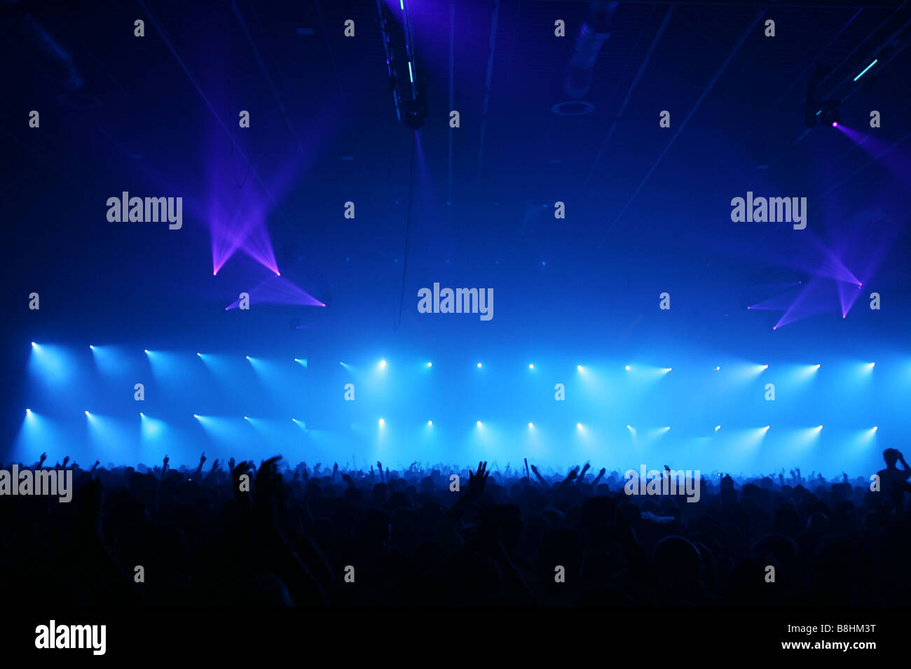 Large crowd and colorful lights and lasers at a houseparty in the