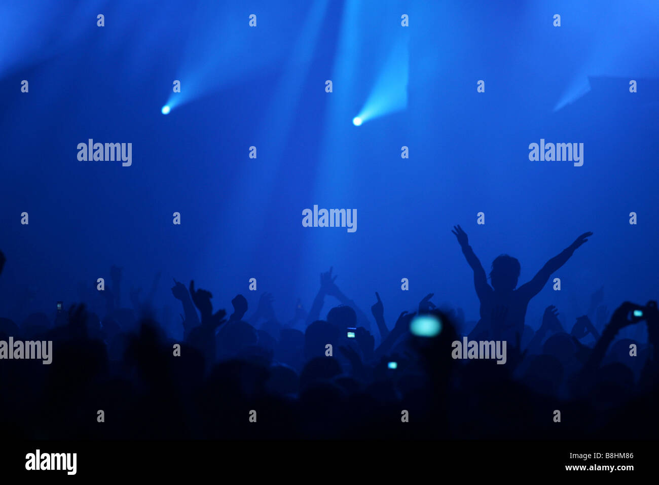Large crowd and colorful lights and lasers at a houseparty in the