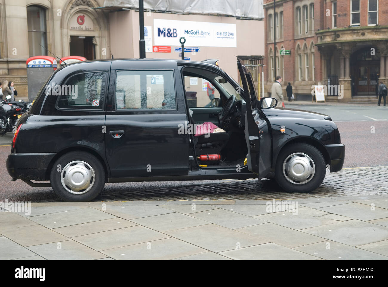 Open taxi cap parked by the curb with a fire extinguisher under the driver's seat Manchester city centre UK Stock Photo