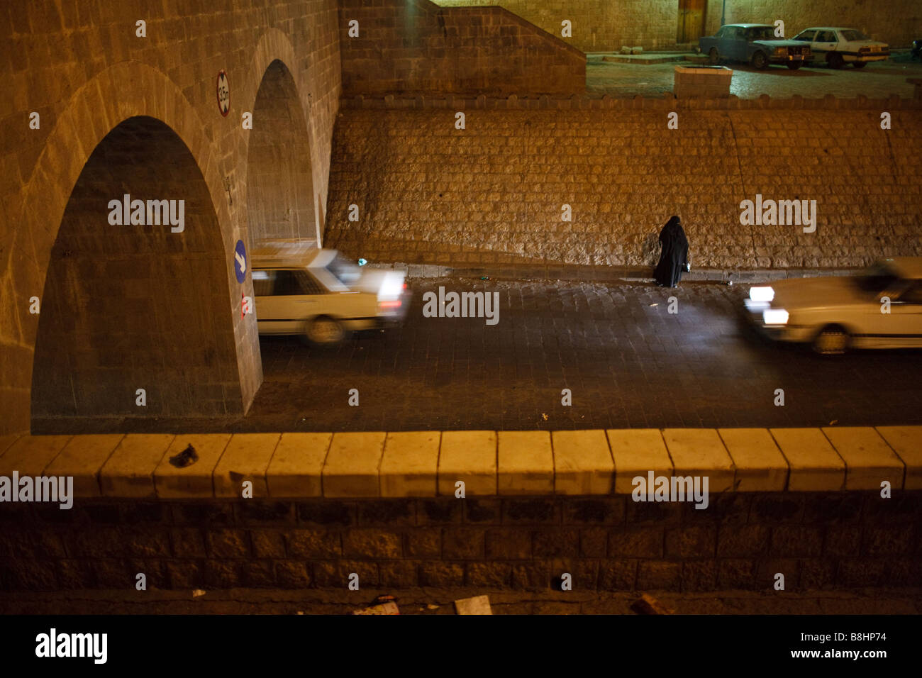 A woman and cars on the road at night in the old city of Sana'a in Yemen Stock Photo