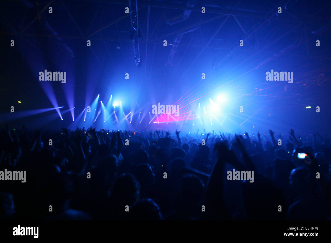 Large crowd and colorful lights and lasers at a houseparty in the