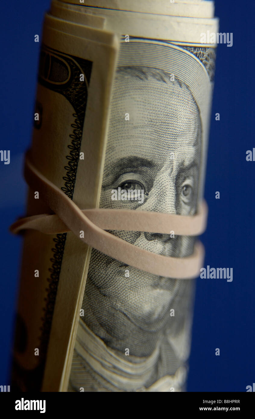 roll of money with rubber band across ben franklins mouth Stock Photo