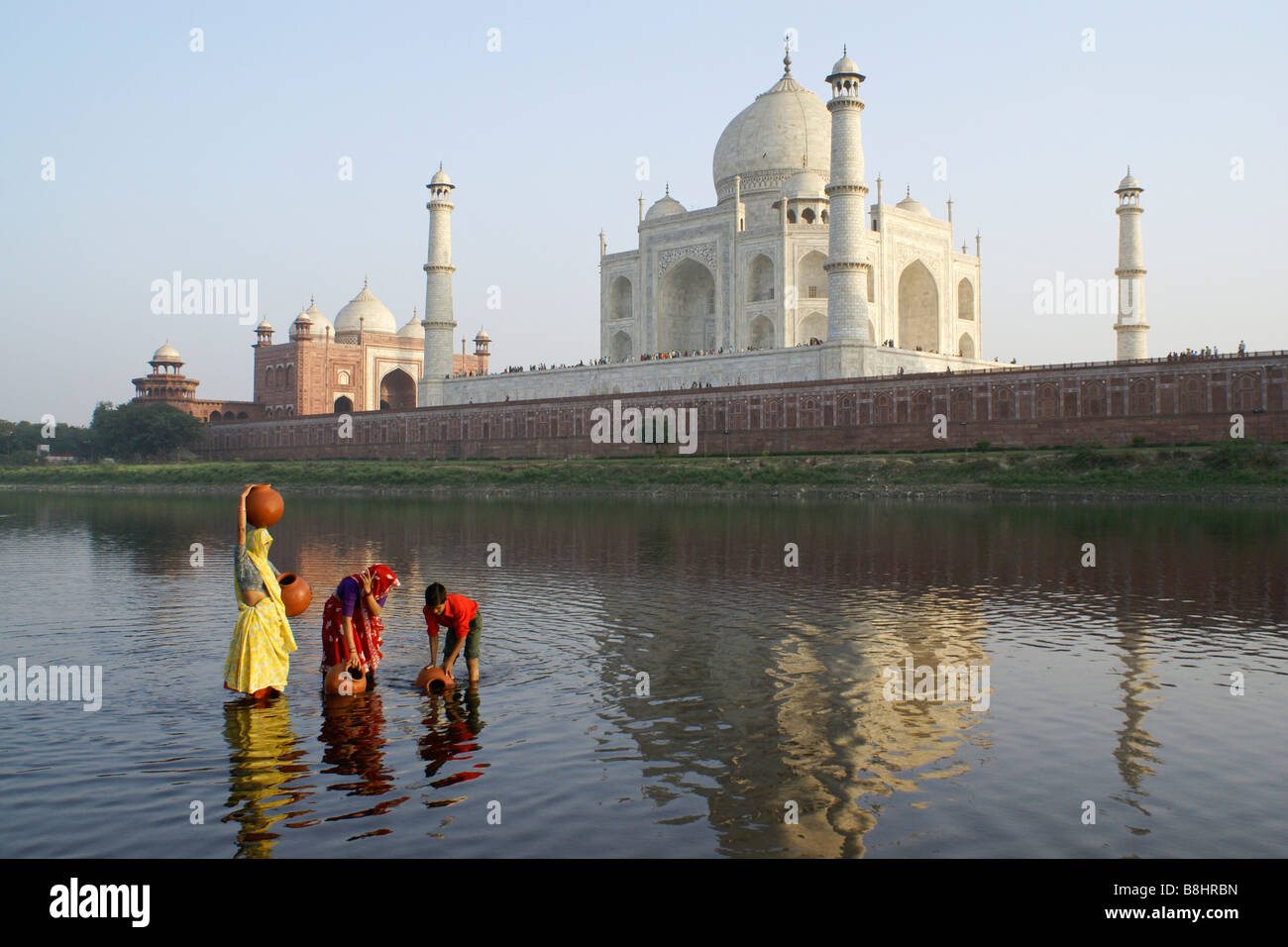 Women and boy getting water from Yamuna River with Taj Mahal in background, Agra, India Stock Photo