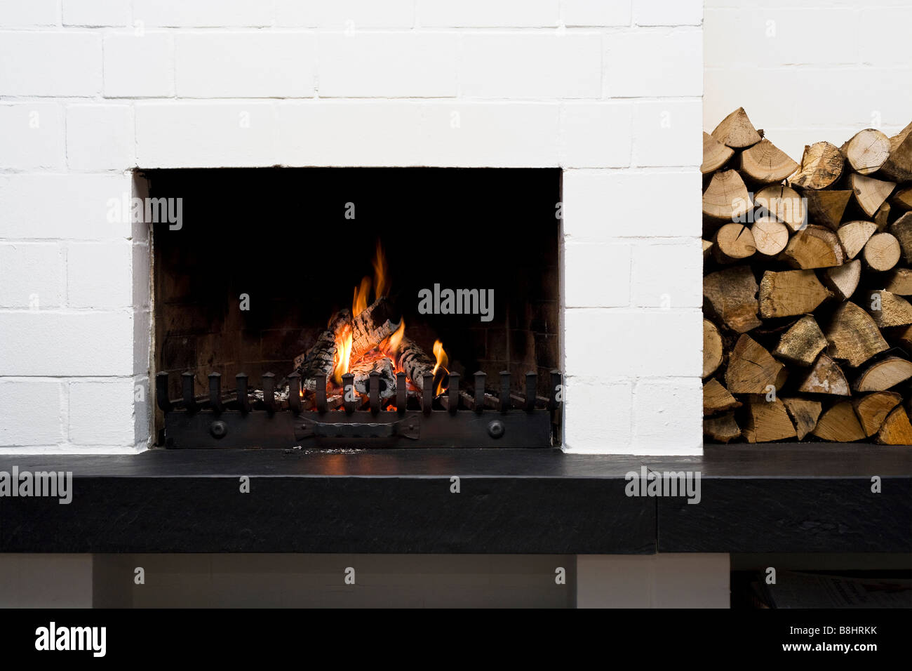 open fireplace and stacked logwood in living-room Stock Photo