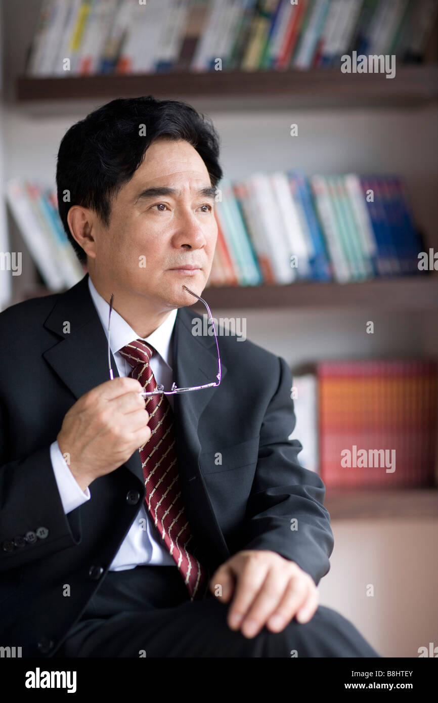 Businessman sitting on chair holding glass in office Stock Photo - Alamy