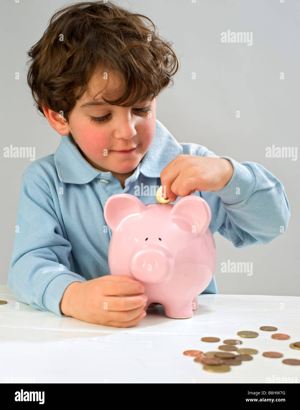 boy inserting a coin to a piggy bank Stock Photo - Alamy