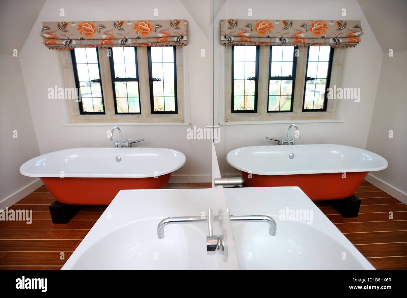 A MODERN LUXURY BATHROOM WITH FREESTANDING BATH REFLECTED IN THE BASIN MIRROR UK Stock Photo
