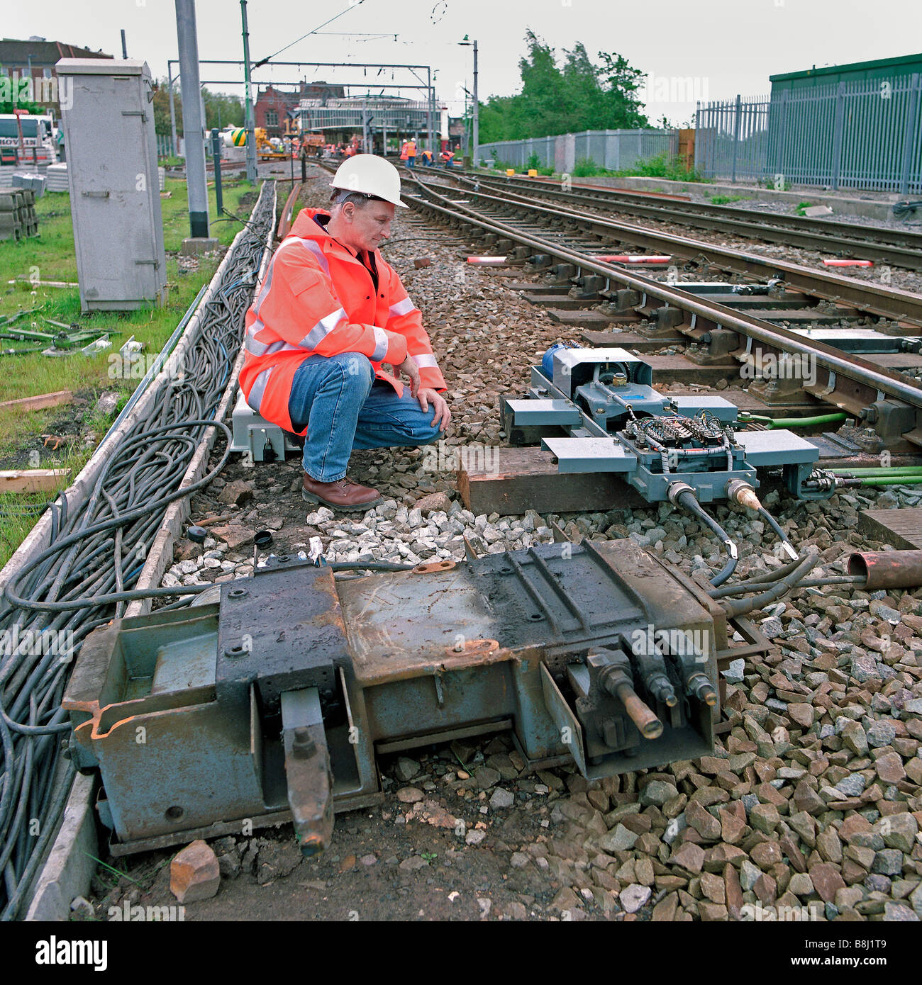 Contractor examines a newly replaced points motor during an upgrade programme on a bust railway system. Stock Photo