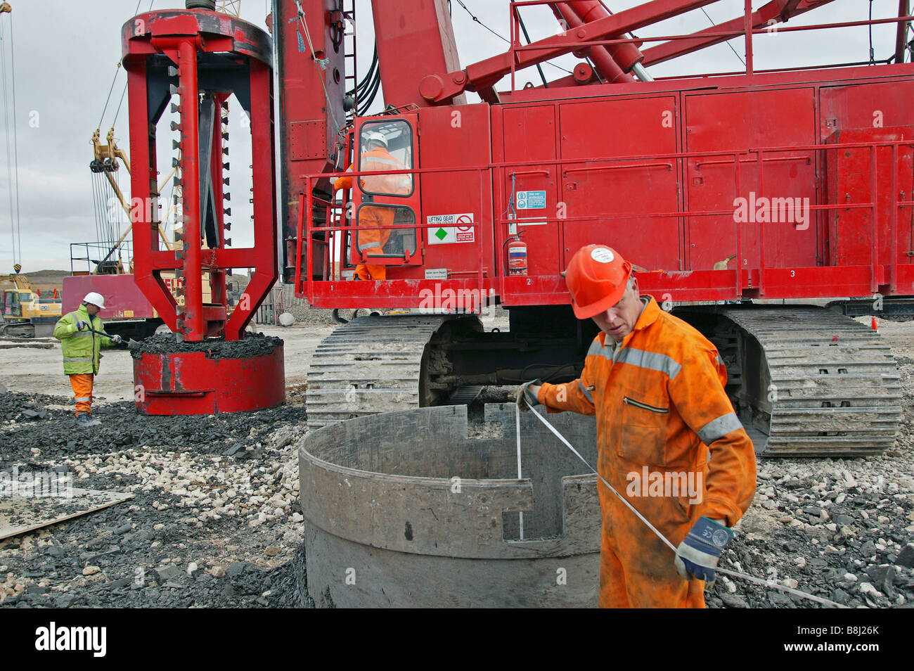 Contractor measures the depth of foundation pile excavated by rotating drill within special bucket designed to retain soft earth Stock Photo