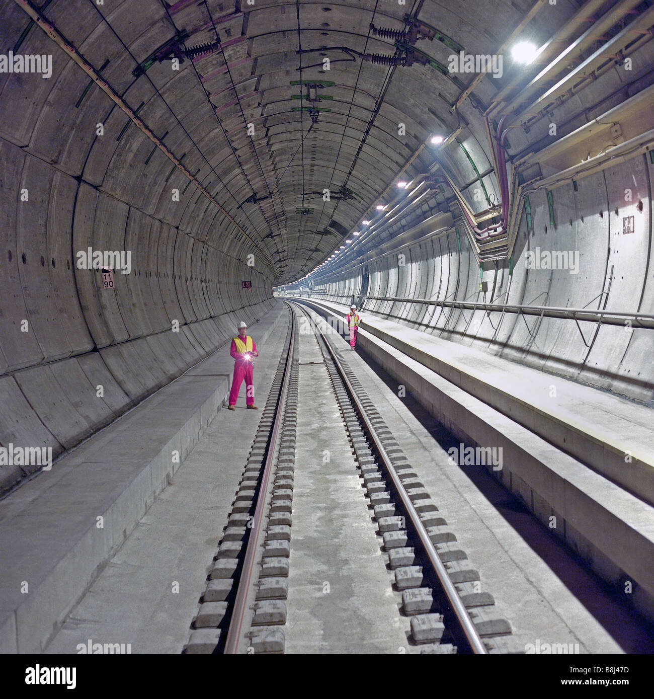 Eurotunnel monitoring engineers examine completed section of Channel Tunnel  rail tunnel with permanent tracks and walkways Stock Photo - Alamy