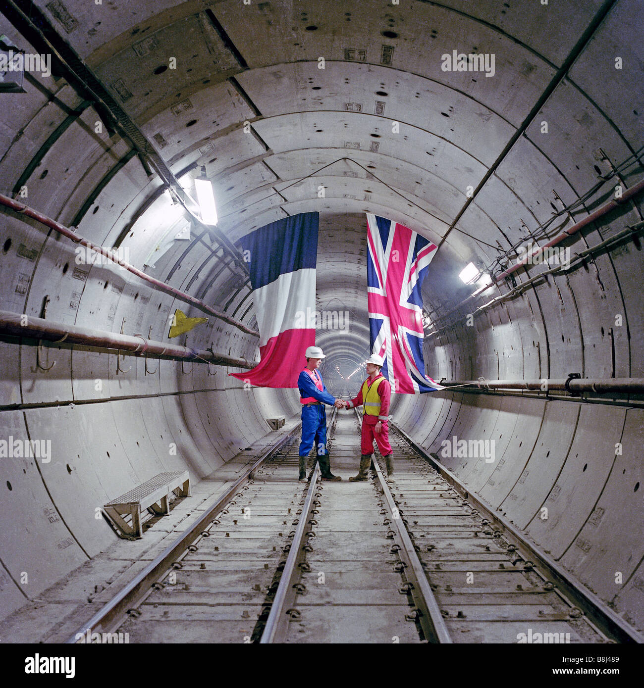 In a Channel Tunnel rail tunnel, a French and UK engineer commemorate the first linking of the two countries since the Ice Age. Stock Photo