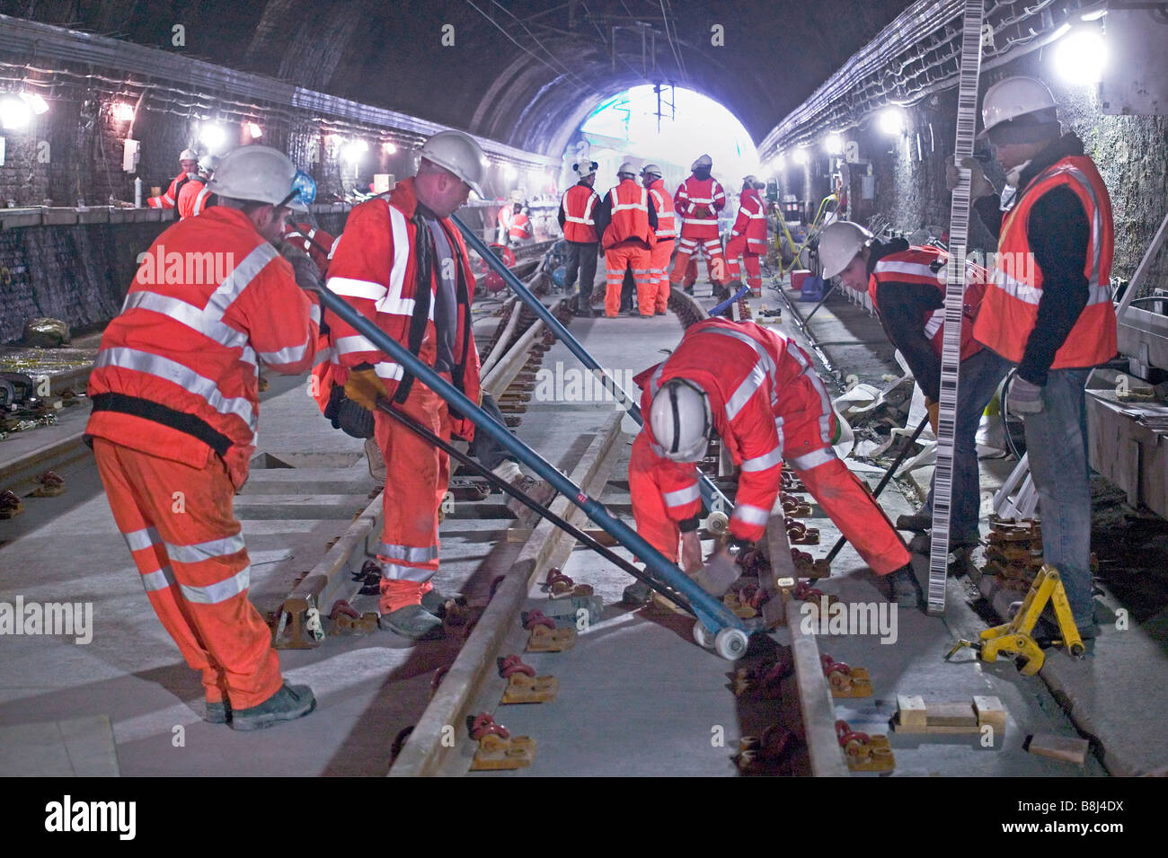 Rail contractors installing new rails during tunnel trackwork replacement project on a busy city railway. Stock Photo