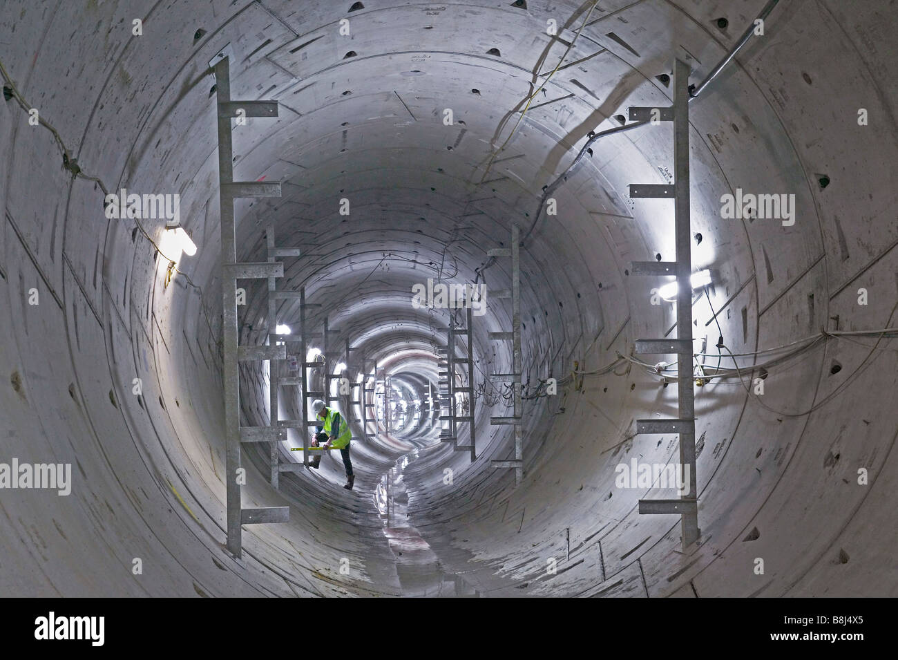 Engineer examines newly installed brackets which will carry the permanent equipment to be installed in this power cable tunnel. Stock Photo
