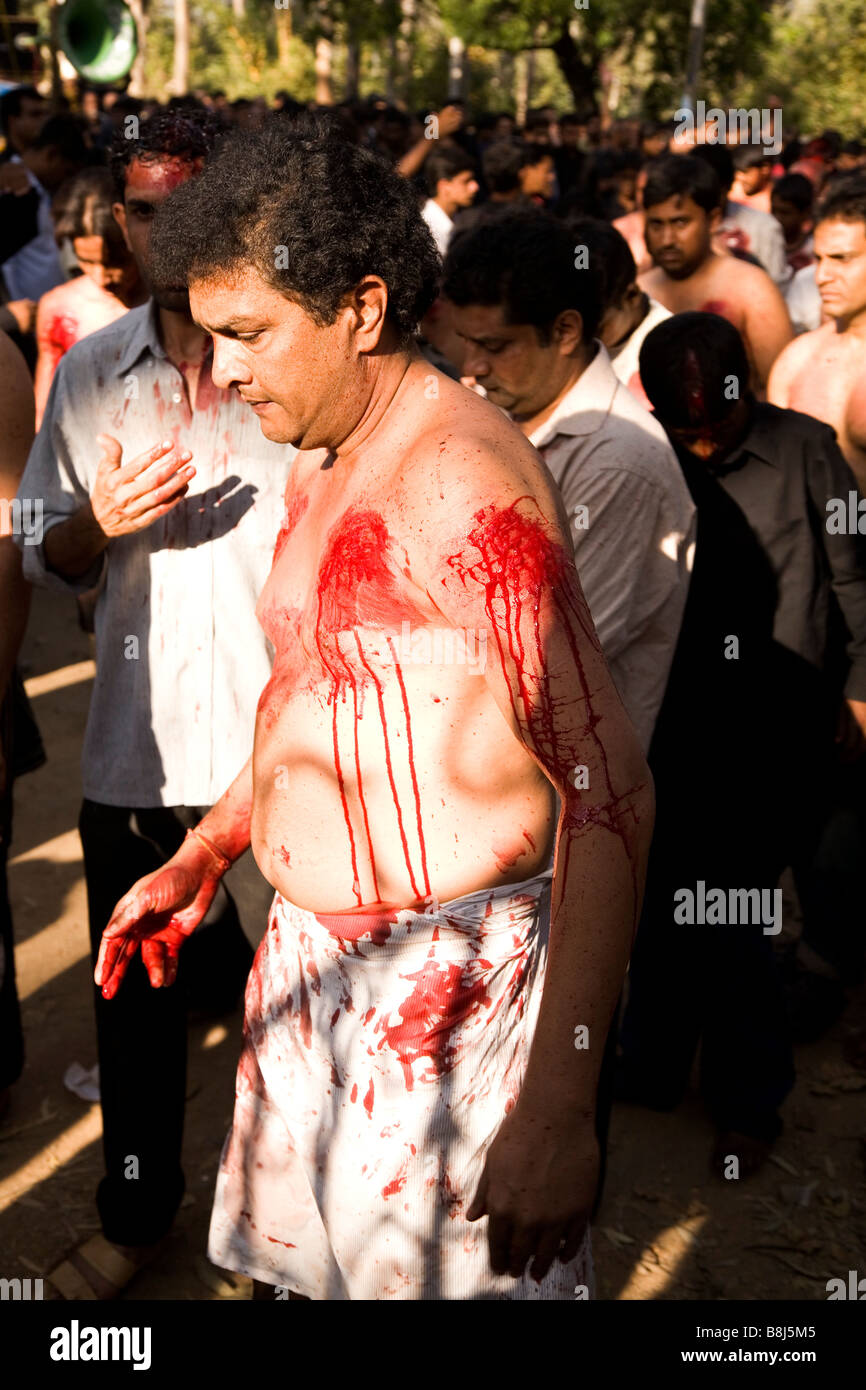 A man bleeds from the shoulder and chest among a gathering of Shia Muslims, celebrating Day of Ashura (festival of Karbala) Stock Photo
