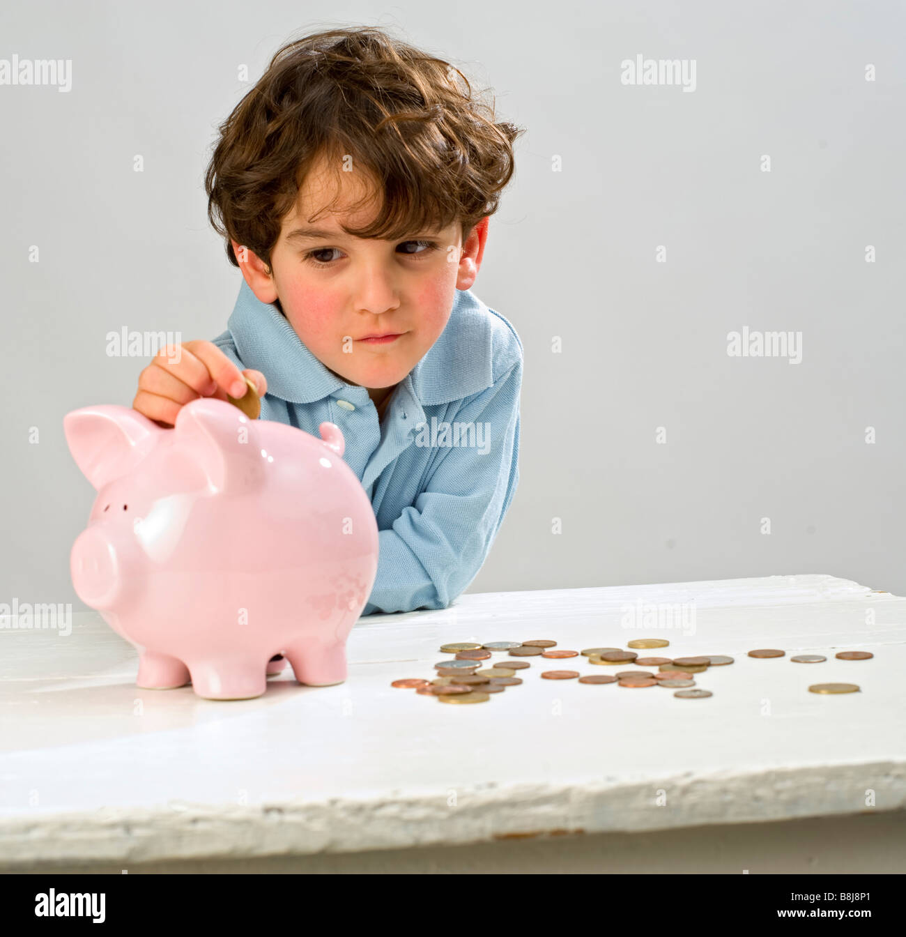 boy inserting a coin in a piggy bank Stock Photo - Alamy