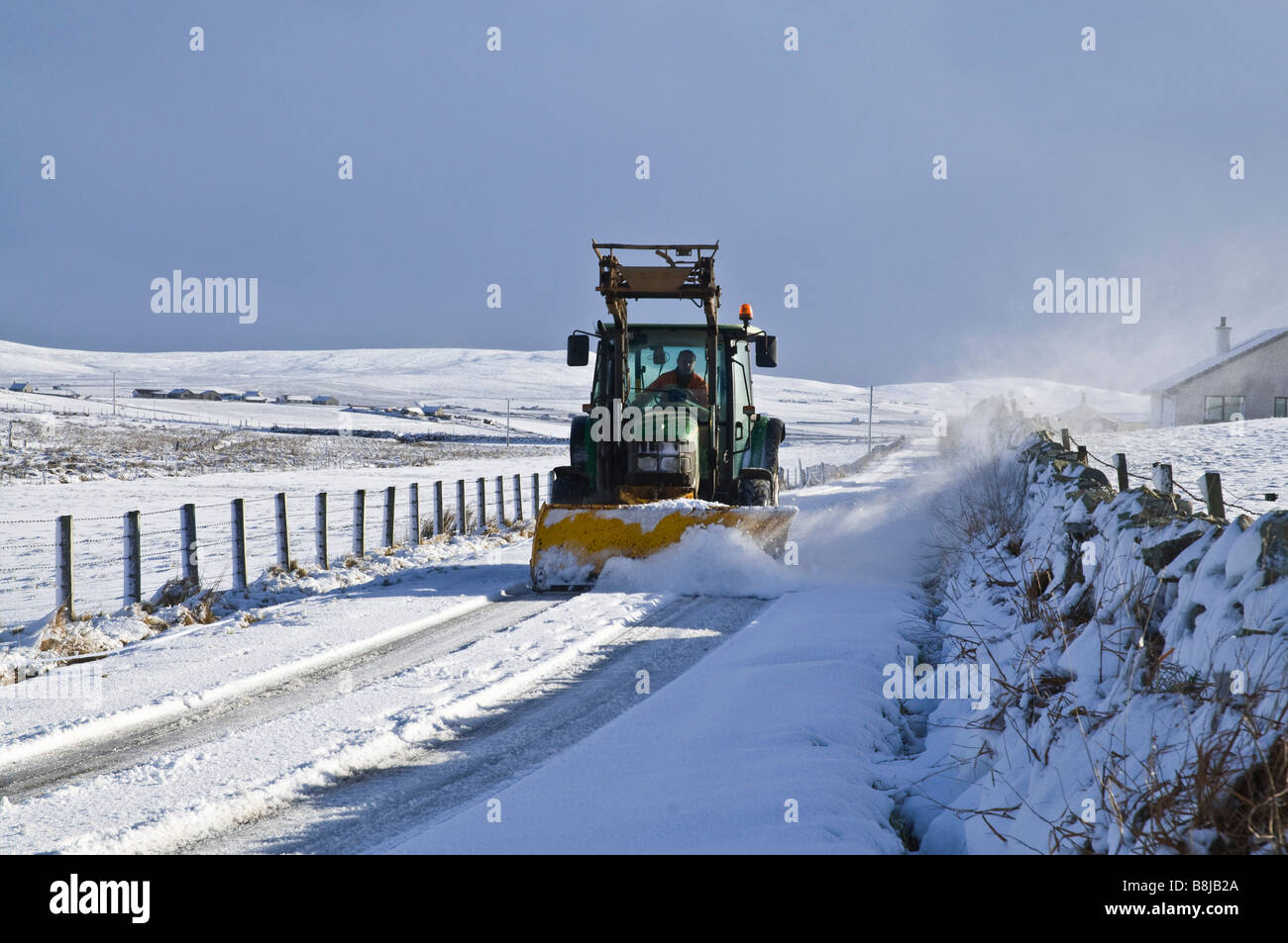 dh  ROADS UK Farm tractor snowplough clearing snow from Orkney country winter roads snowplow vehicle plow snowy lane road Stock Photo