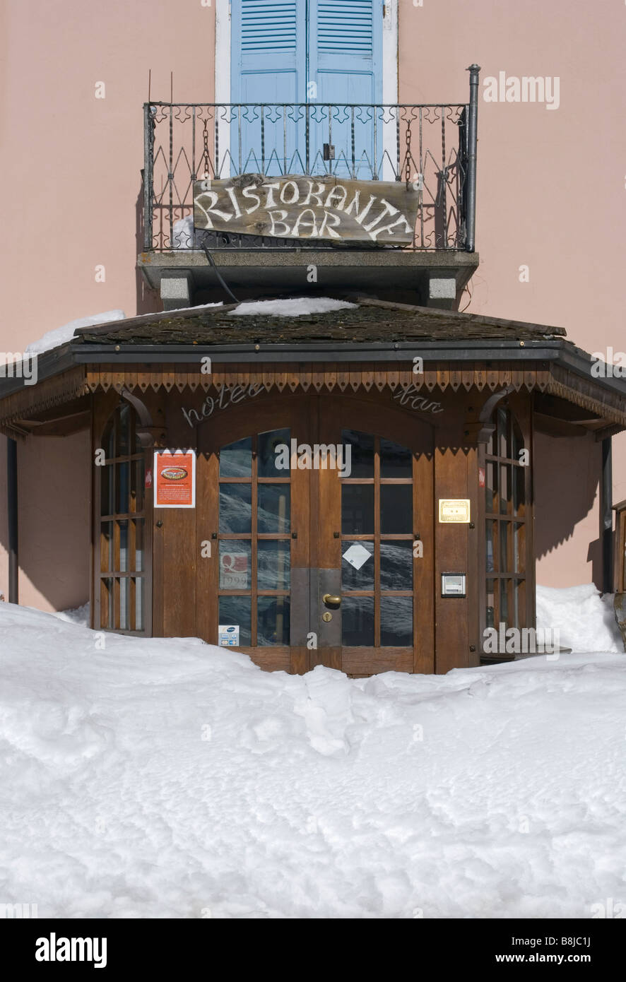 the snow buried entrance of a restaurant in Montespluga before Splugen Pass Italian Alps Italy Stock Photo