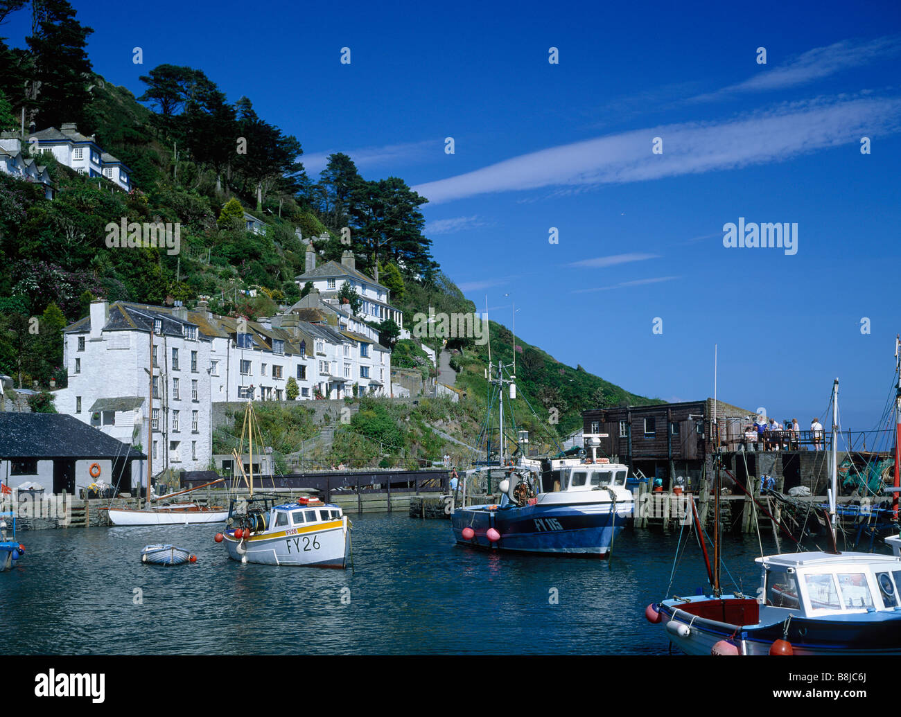 Harbour Boats moored Fishing nets Harbour wall People White houses on hill POLPERRO CORNWALL ENGLAND Stock Photo