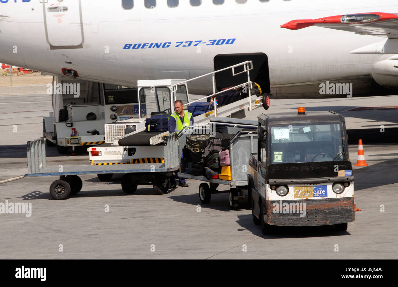 Baggage handler unloading luggage from a Boeing 737 jet aircraft at