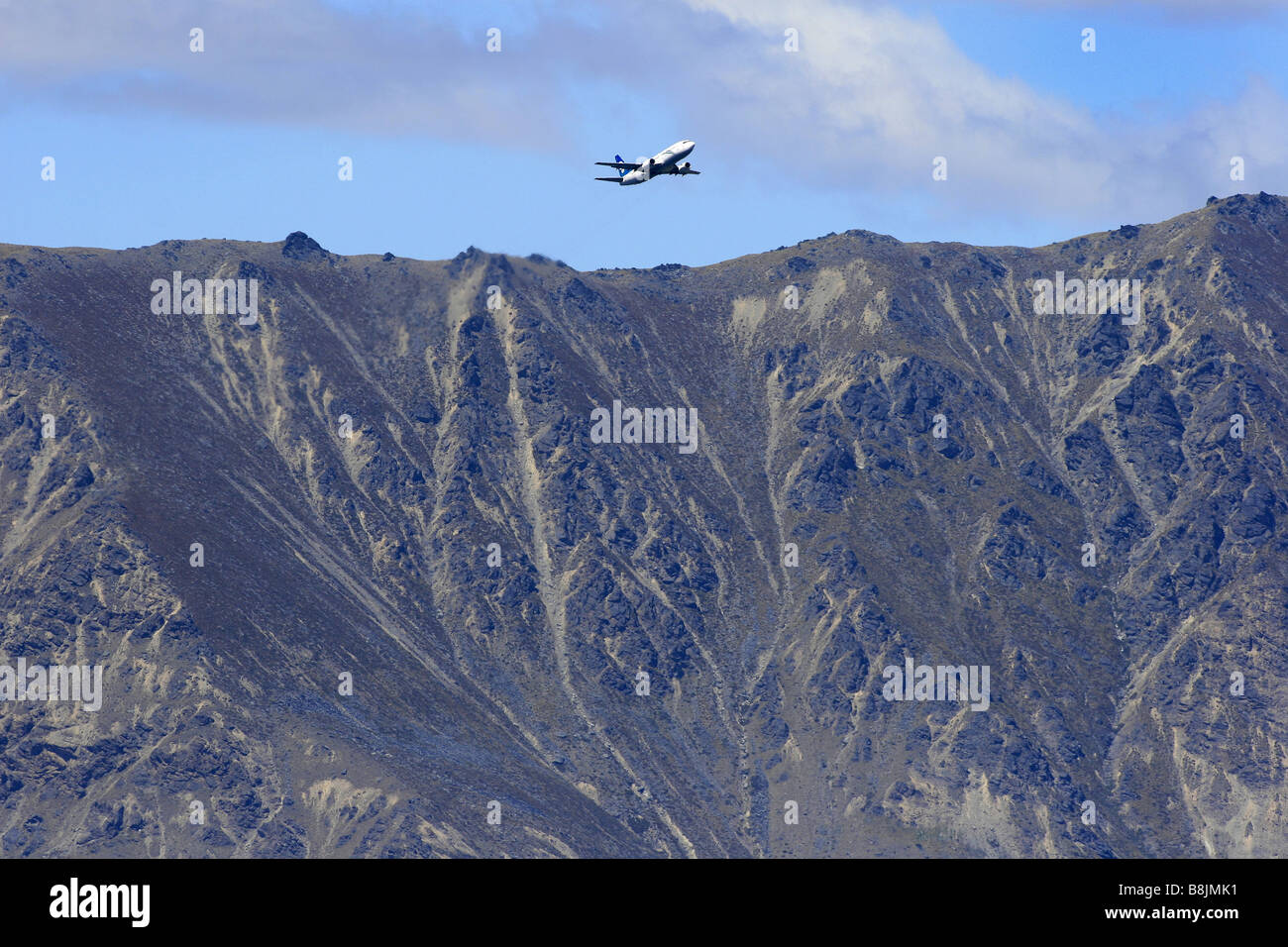 A plane takes off from Queenstown Airport, with The Remarkables in the background, New Zealand Stock Photo
