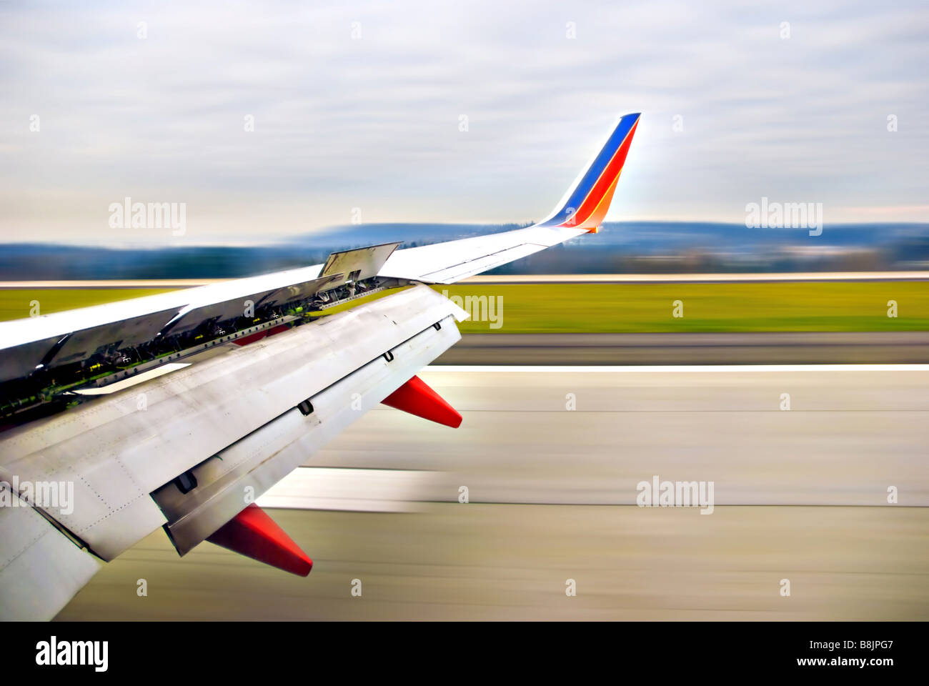 Airplane wing open upon landing on runway in motion Stock Photo