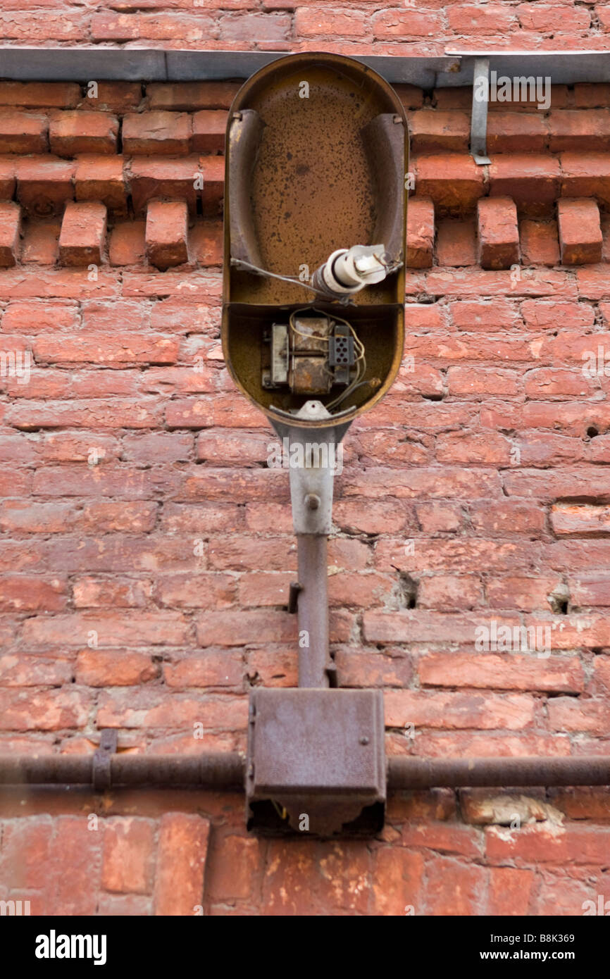 Old broken lantern with shattered bulb over red brick wall. Stock Photo