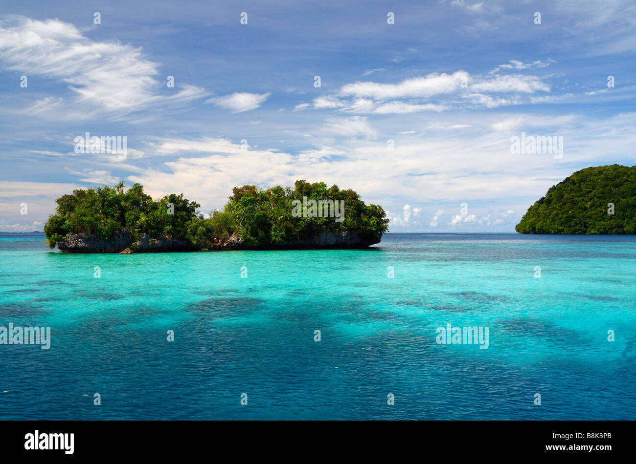 Rock islands of Palau surrounded by shallow reefs with turquoise water and blue sky with light clouds Stock Photo