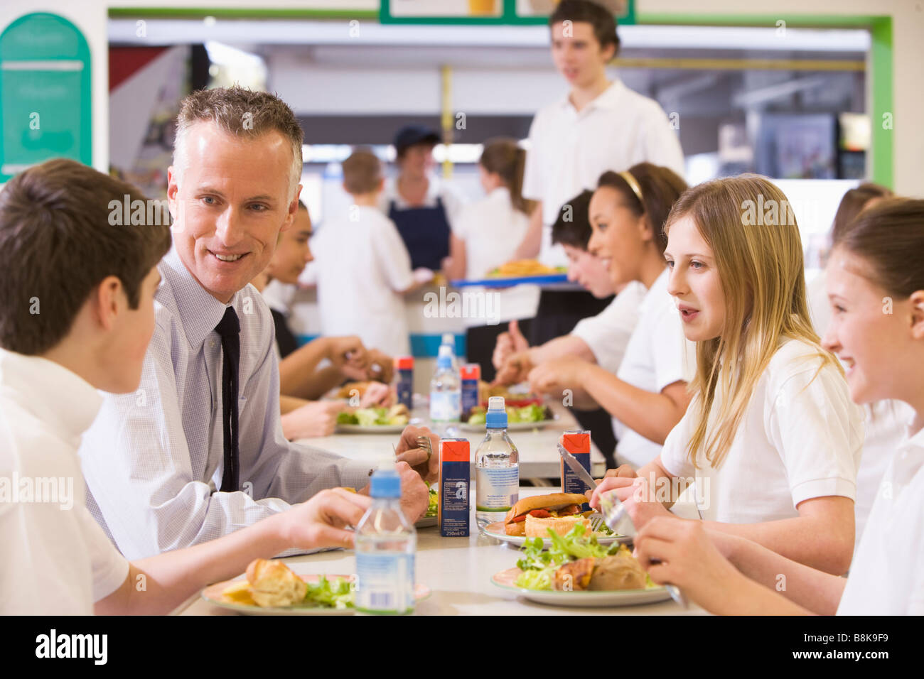 Students and teacher having lunch in dining hall Stock Photo