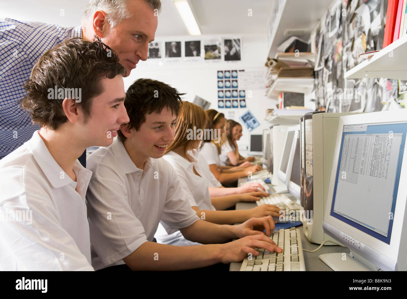 Students working on computer workstations with teacher Stock Photo Alamy