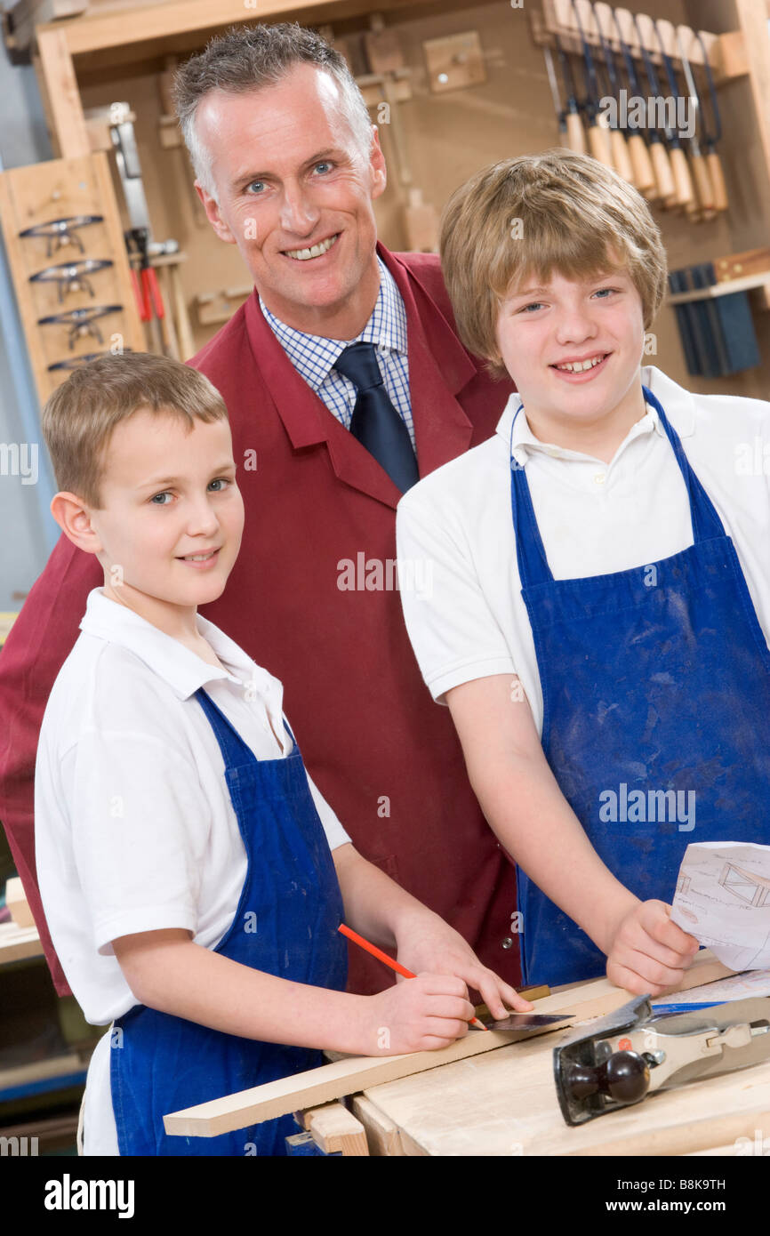 Male students reviewing woodworking plans with teacher Stock Photo Alamy