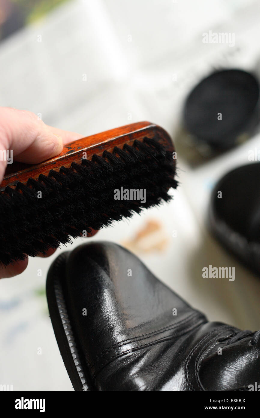 Polishing black shoes with shoe brush and shoe polish Stock Photo
