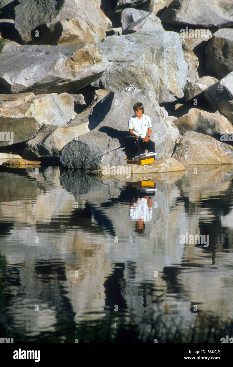 teen boy fish pole lake rock reflection water set surface shine