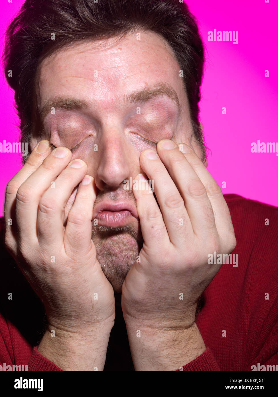 A tired man holding his eyelids Stock Photo