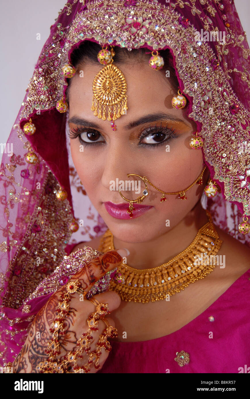 Pretty Asian or Indian Bride wearing a red dress and ornaments Stock Photo