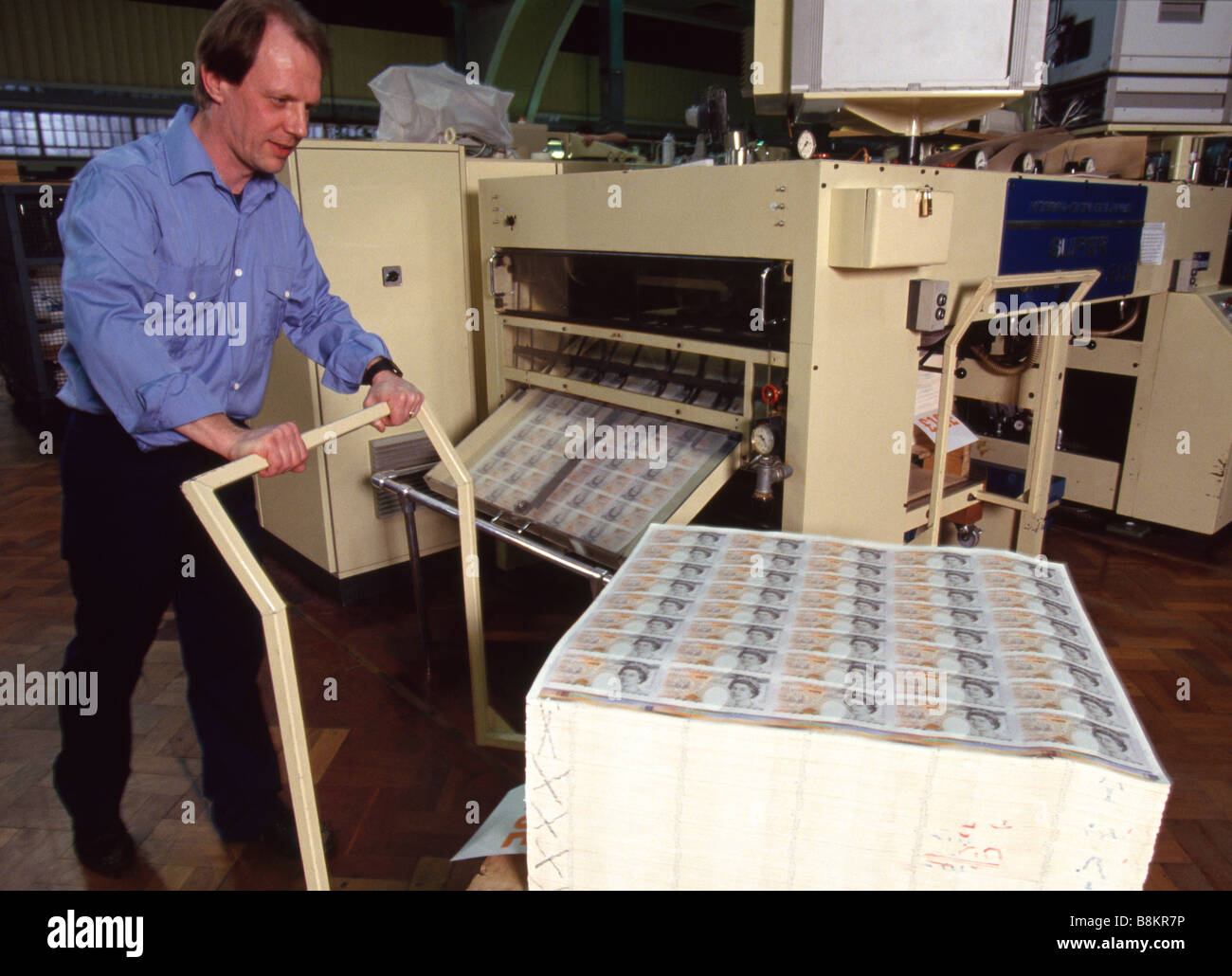 Bank of England Printing Works in Debden Essex now De La Rue, A printer wheels a trolley of freshly printed uncut 10 pound notes Stock Photo