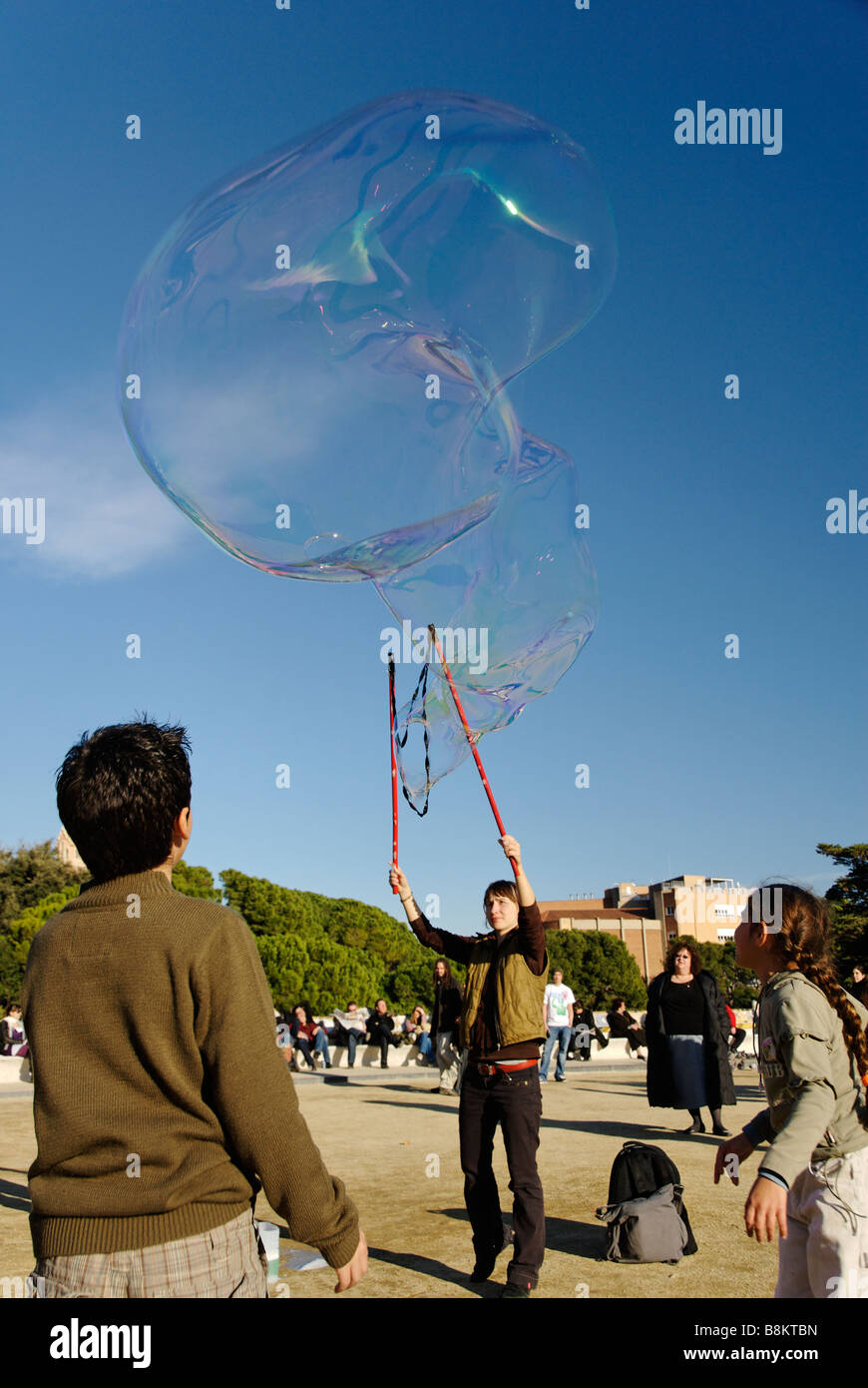 Performing street artist blowing giant bubbles in Park Güell designed by Catalan artist Antoni Gaudí Barcelona Spain Stock Photo
