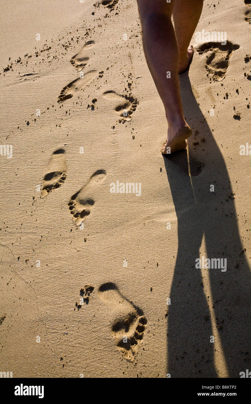 A man walks on the beach passing other footprints in the sand Stock ...