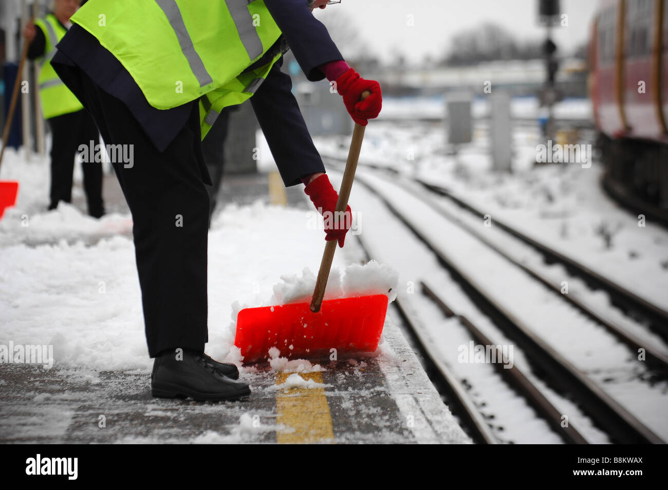 Railway maintenance workers clear the snow covered platform at Wimbledon station, south west London. Stock Photo