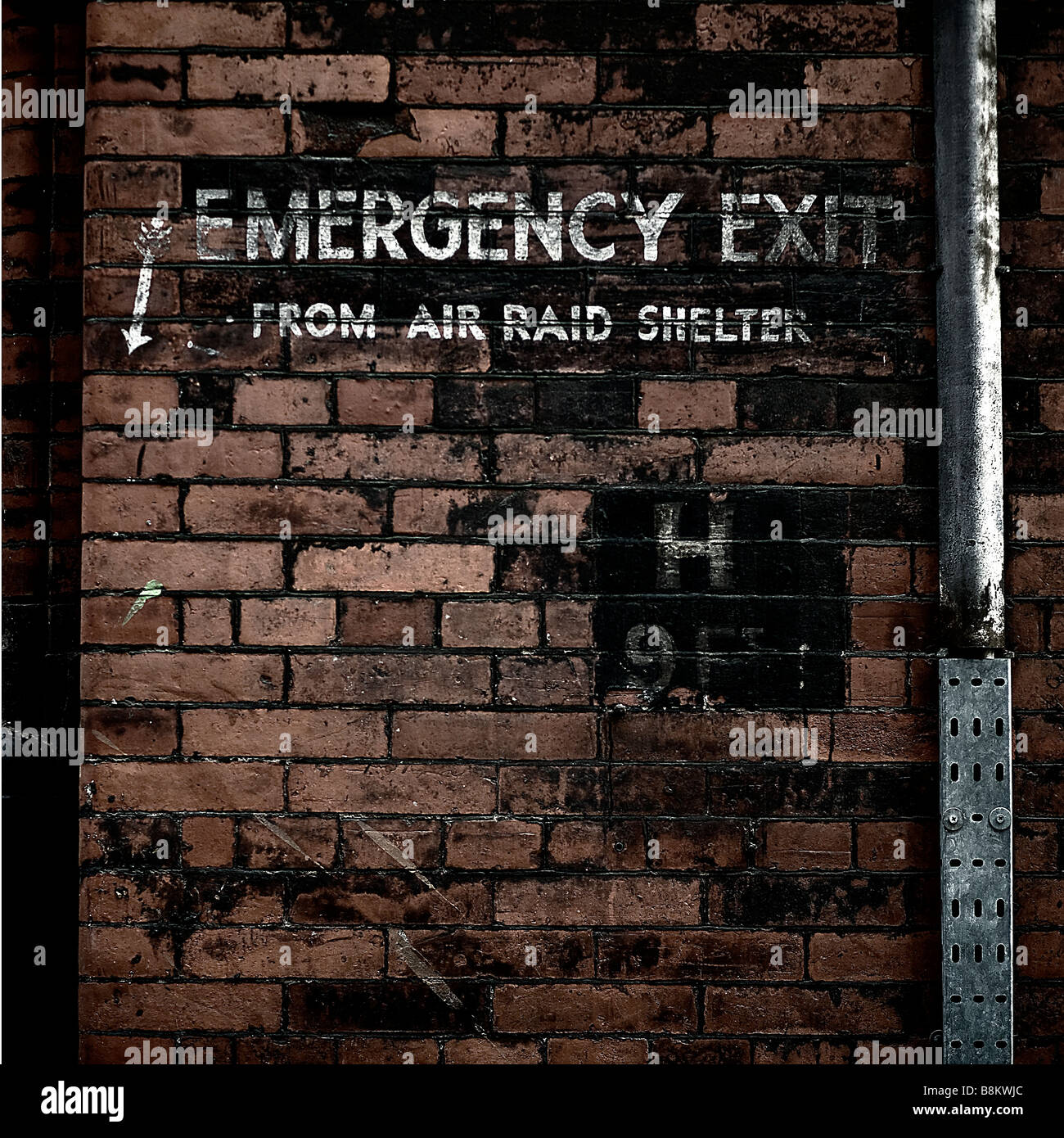 old world war 2 'emergency exit from air raid shelter' sign against an old brick wall Stock Photo