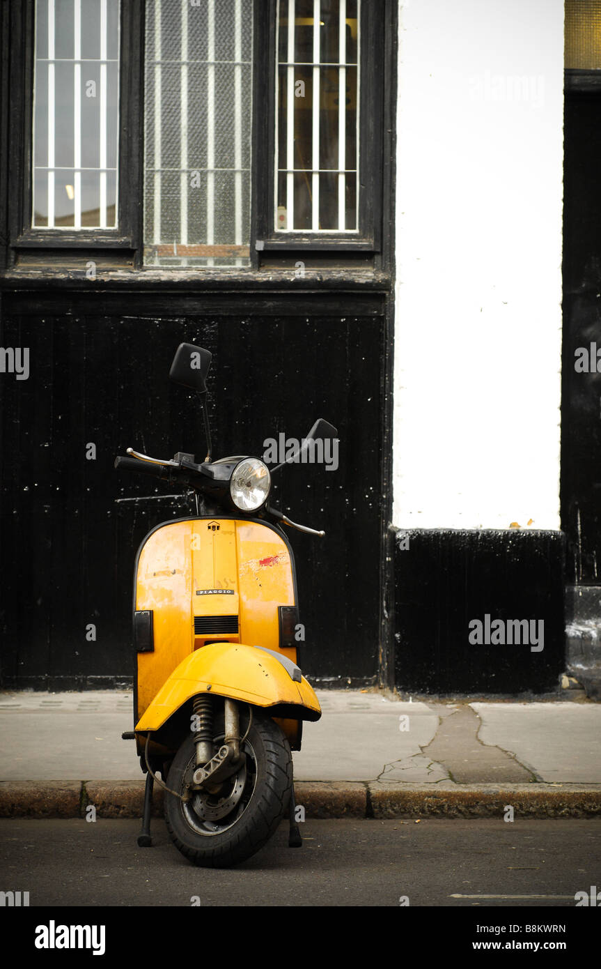 A sole yellow Vespa scooter in Shorditch, East London, parked on a roadside in Shorditch, London. Stock Photo