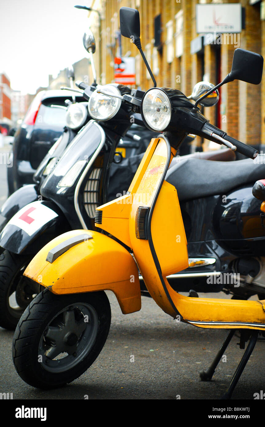 A line of Vespa scooters in Shorditch, East London, on a roadside with