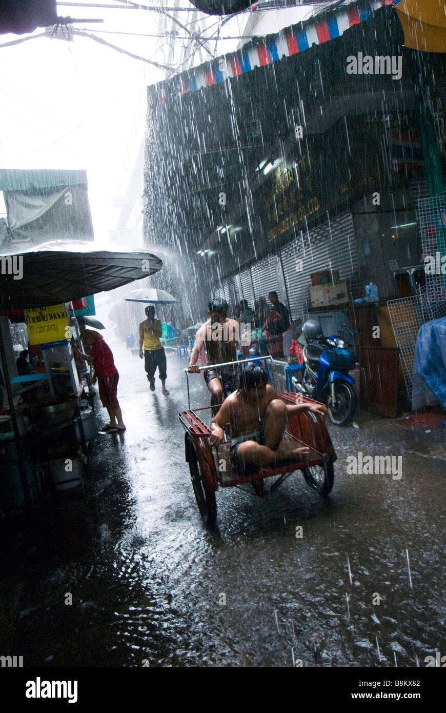 People caught in monsoon downpour in alleyway Chinatown central Bangkok Thailand Stock Photo