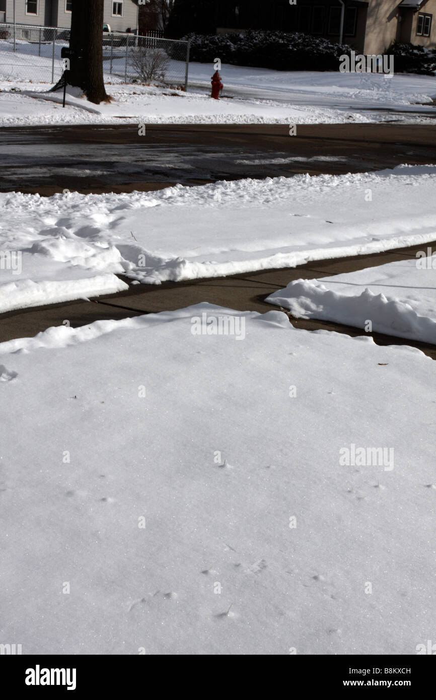 Cleared sidewalks and snow covered yard lawn Stock Photo