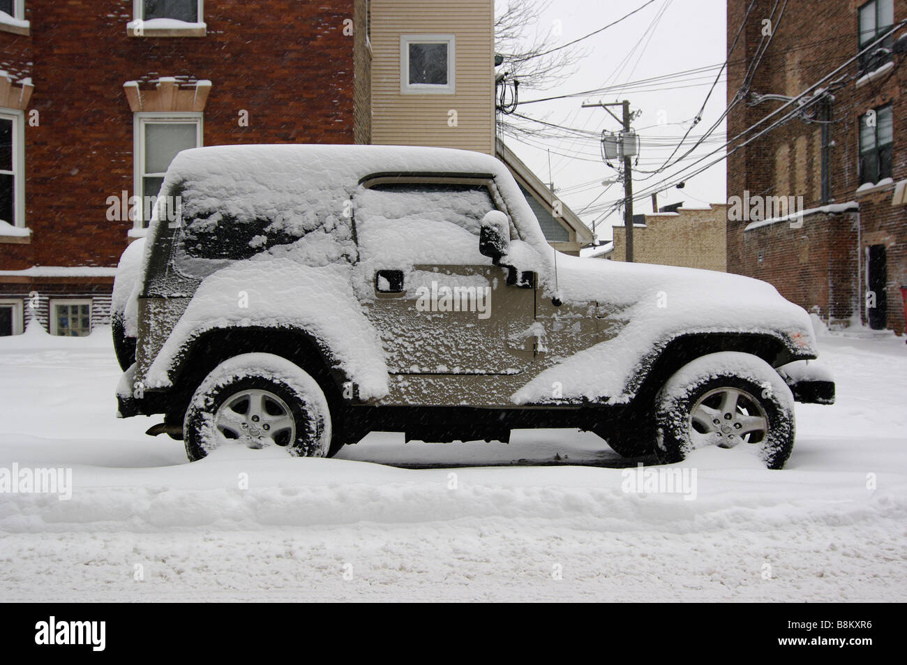A Jeep Wrangler 4x4 SUV frozen on a city street covered in snow and ice. Stock Photo