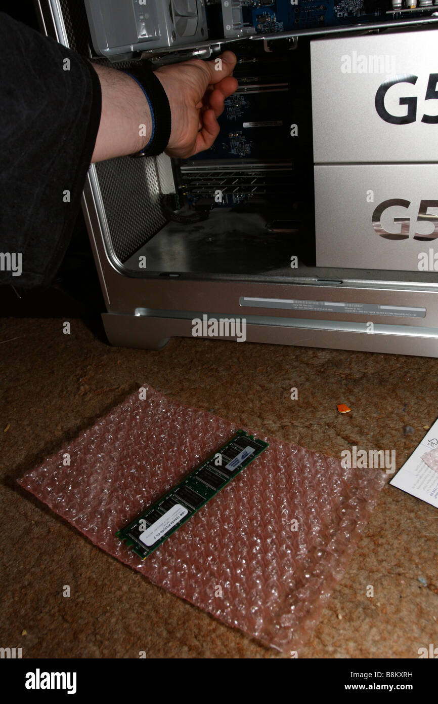 Man's hand pushing RAM into slots on Apple PowerMac G5, late 2004 dual 2gHz, side  open Stock Photo