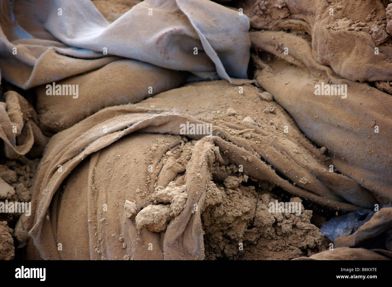 A dirt covered blue tarp at a construction site covers concrete foundation forms for industrial development. Stock Photo