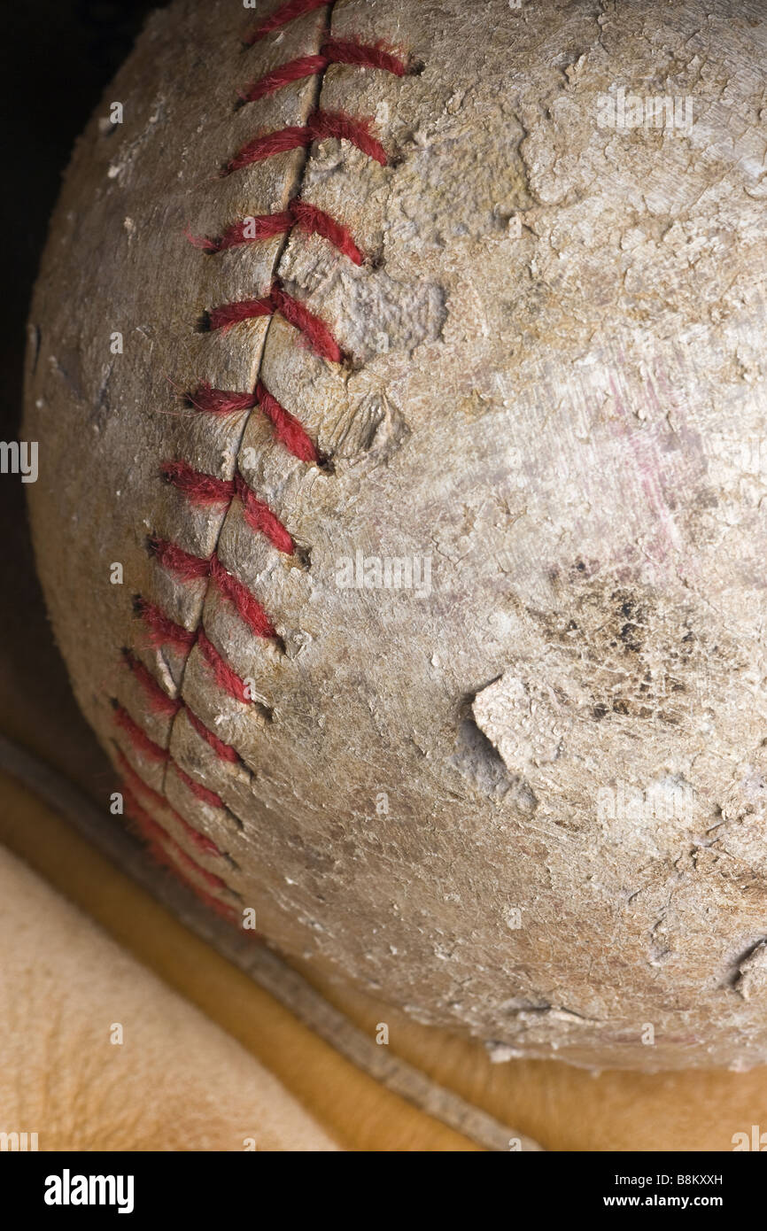 well used softball with red stitching in mitt Stock Photo